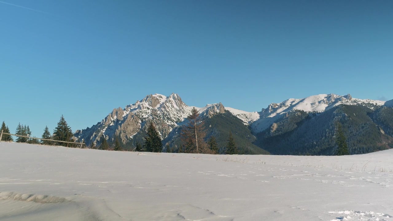 A snow-covered mountain peak on a clear winter day, with rugged slopes and sunlight reflecting off the pristine snow.