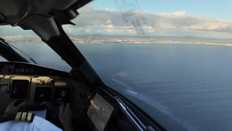 an immersive pilot view (copilot seat) in a real time approach to palma de mallorca airport, overflying the mediterranean sea with the runway ahead. copilot is flying the jet. daylight with few clouds