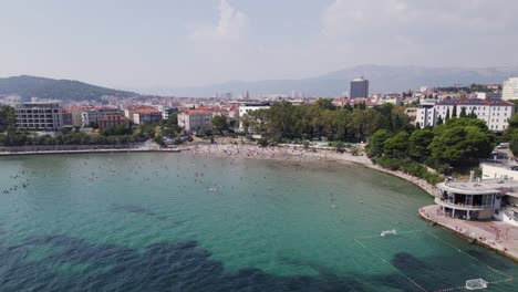 Beach-in-Croatian-city-of-Split-full-of-unrecognisable-people-swimming,-aerial