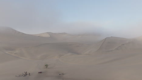 drone shot near huacachina peru behind the dunes on a cloudy day during the mist in the morning log