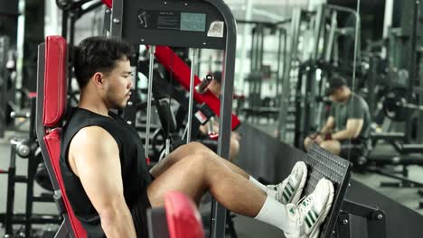 a man performs leg presses in a modern gym, showcasing strength and focus. bright lighting highlights the energetic atmosphere