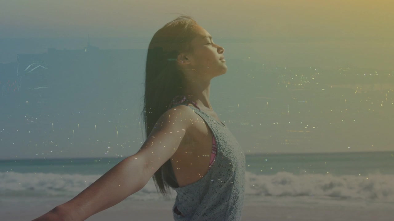Sunlight coaxing woman on sandy shore by ocean waves, opening arms and tilting head for wellness