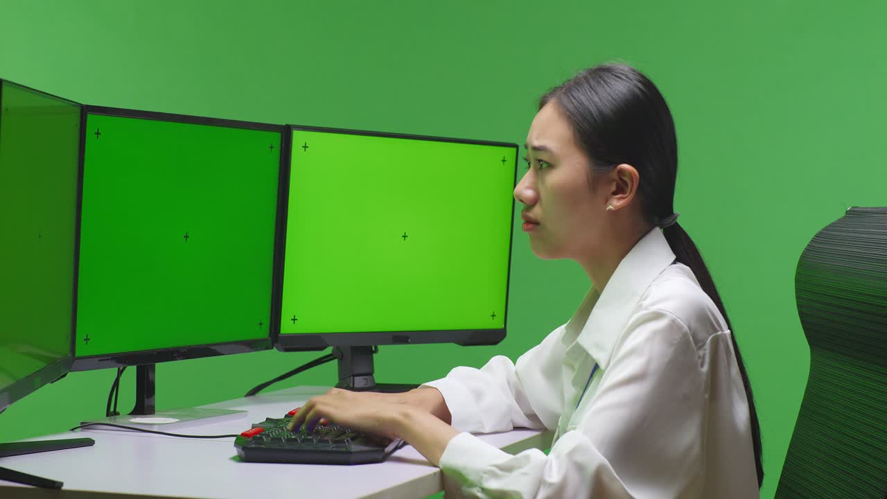 mujer trabajando en una computadora frente a una pantalla verde