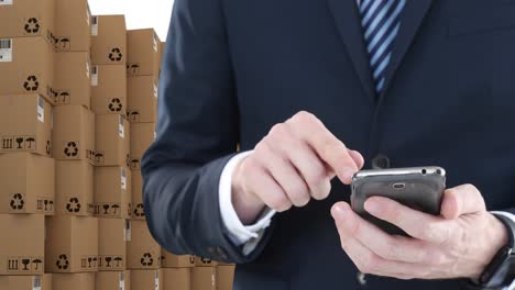 Animation-of-businessman-using-smartphone-with-stacks-of-boxes-on-white-background