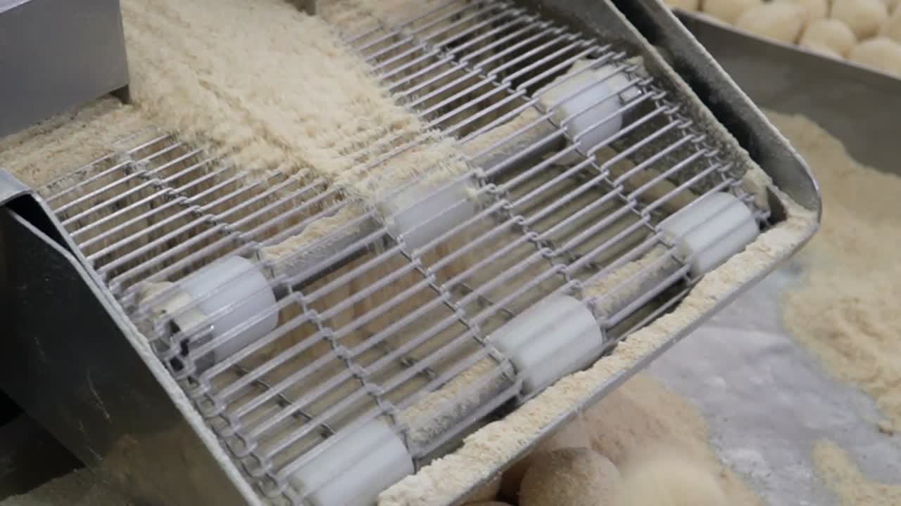 자동화된 달함을 경험하십시오: 클로즈업 은 페이스트리 가게에서 맛있는 과자를 능숙하게 만드는 기계를 포착합니다.