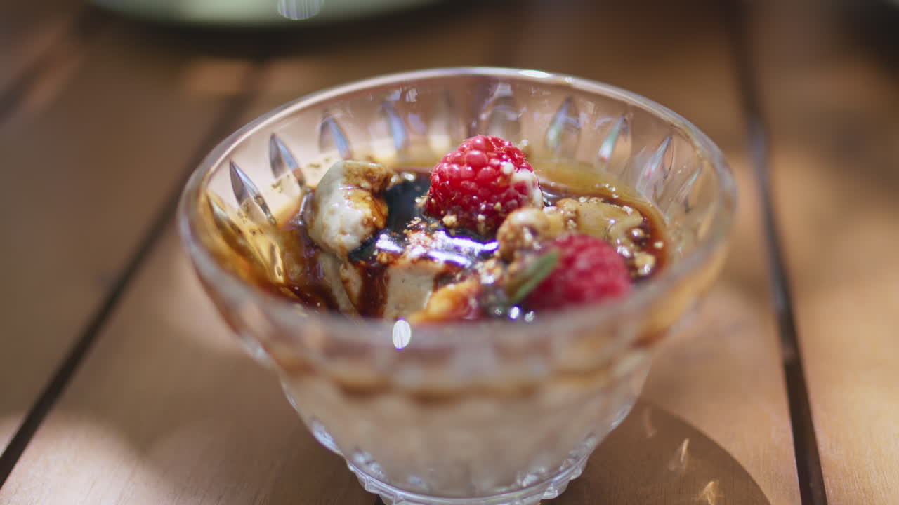 Primo piano di un dessert al caramello con frutti di bosco in un piatto di vetro in un caffè estivo. Gustosa mousse dolce.