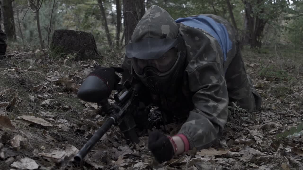 Paintballspelare som kryper på plastunno, slowmotion-skytte