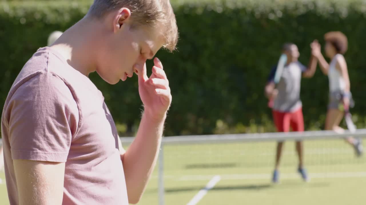 Felice e deluso gruppo di amici di diverse origini che gioca a tennis e festeggia su un campo da tennis