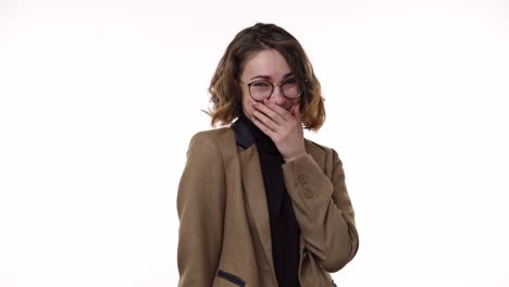 a beautiful european young woman covering her face with a hand, she's embarassed, then she glances at the viewer and waving her hands standing over the white background