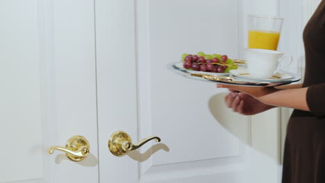 the waiter brings a continental breakfast on a tray to the hotel guest