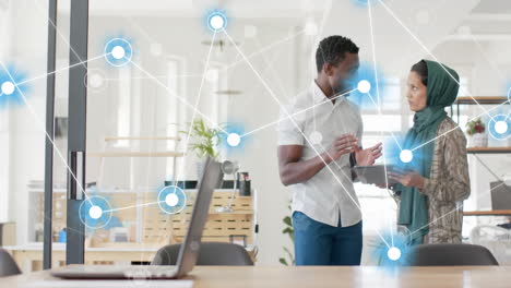 animation of network of connections against diverse man and woman discussing at office