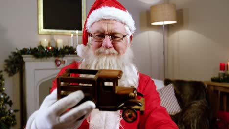 Santa-claus-holding-and-looking-at-a-toy-car