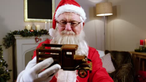 santa claus holding and looking at a toy car