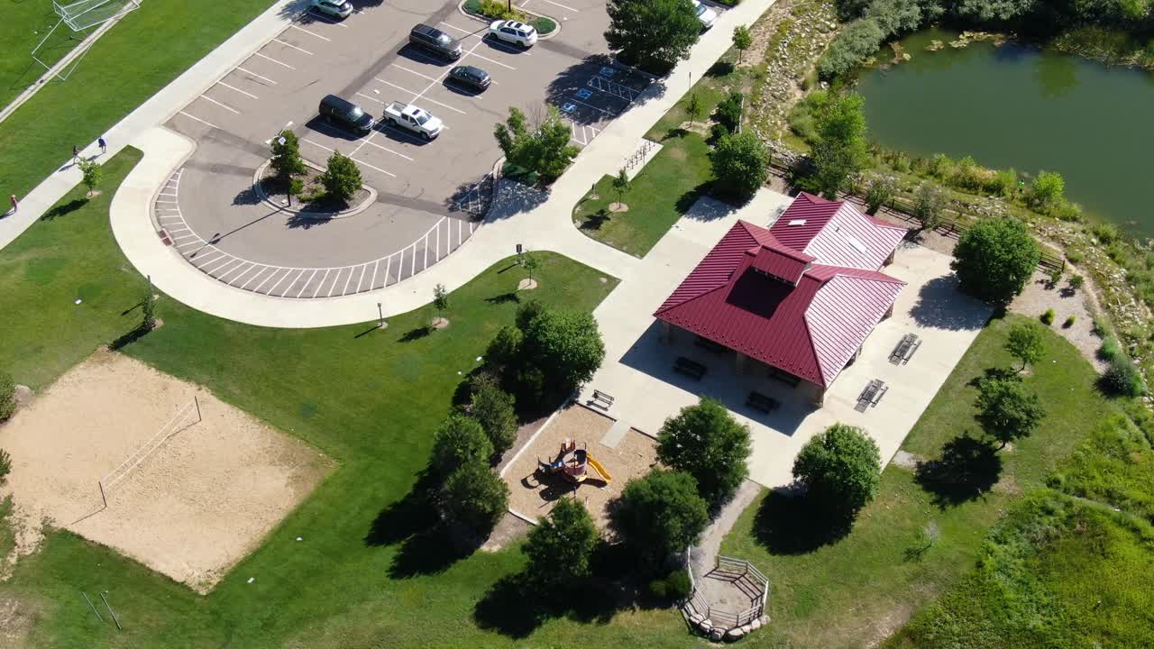 video aéreo, aviones no tripulados sobrevuelan un edificio, junto con el estacionamiento, pinos árboles y un lado como