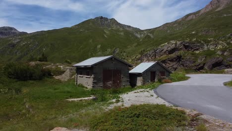 tiny concrete homes in mountains of switzerland, near road, aerial fly away view