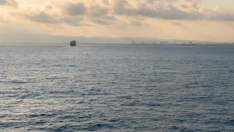 Port-of-Barcelona-at-sunset-skyline-Towers-and-cranes-loading-container-ships-passenger-ferry