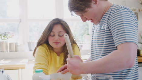 una pareja joven con síndrome de down mezcla ingredientes para una receta de pastel que están horneando en la cocina en casa.