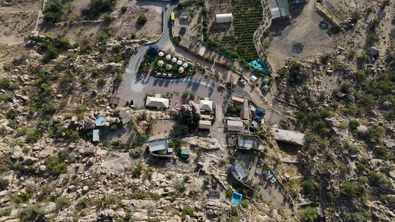 Top down drone shot of a hillside town, sunny evening in Taif, Saudi Arabia