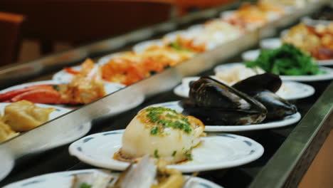 los platos de marisco se mueven en una cinta transportadora en un restaurante todo incluido