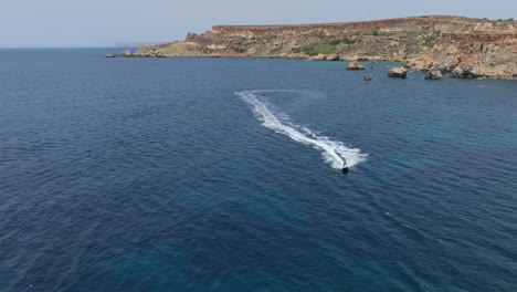 Sailing-Motorboat-Over-Beach-Near-Qarraba-Bay-In-Lido,-Malta