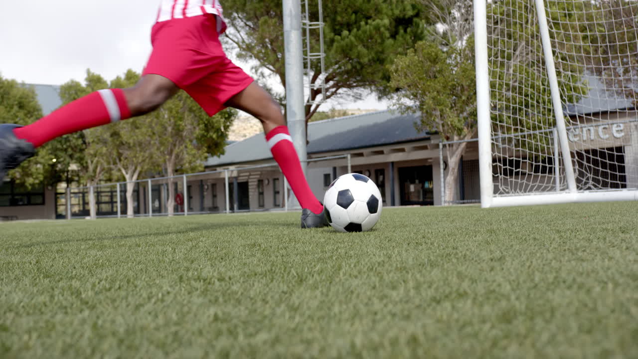 Kicking soccer ball towards goal, african american male player ...
