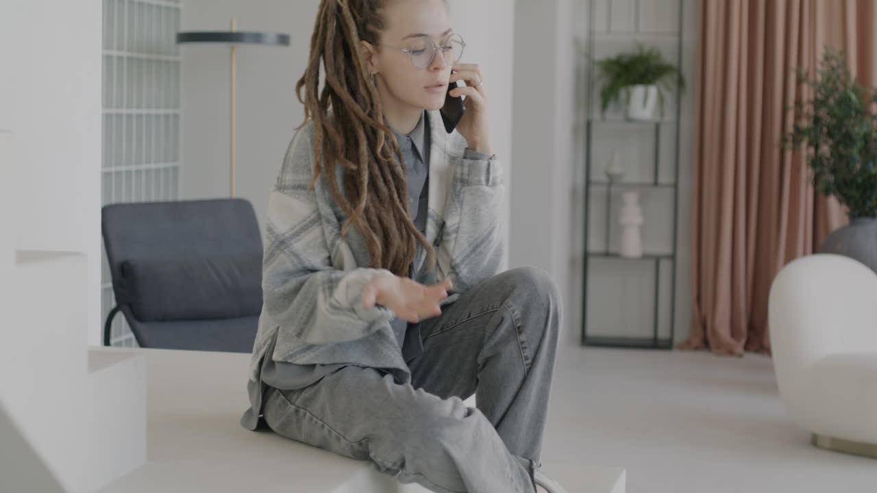 Donna che parla al telefono seduta sulle scale in una casa moderna