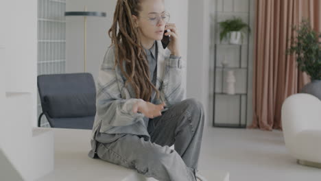 woman talking on phone while sitting on stairs in modern home