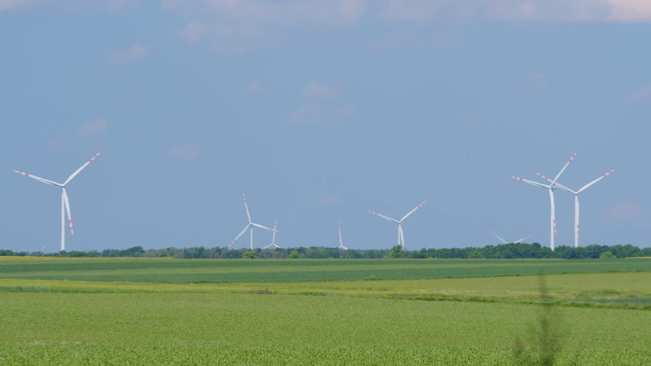 멀리 떨어진 농지에서 청정 에너지를 생산하는 많은 터빈을 가진 풍력 공원, 파란 하늘