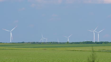 wind park with many turbines producing clean energy in remote farmland, blue sky