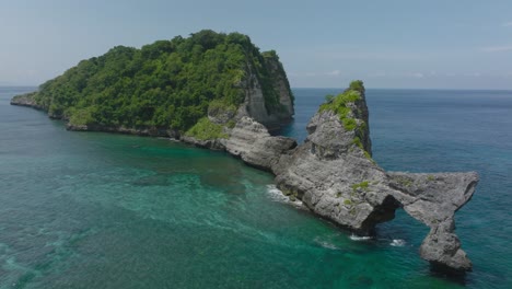 wild tropical remote island with steep rock cliffs, nusa batupadasan, aerial