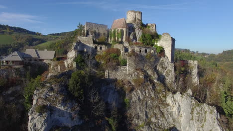 Drohnenaufnahme-Einer-Ruine-Auf-Einem-Felsen-Bei-Sonnenuntergang,-Die-Hochfliegt,-Während-Sie-Sich-Nach-Unten-Neigt,-4k-Uhd