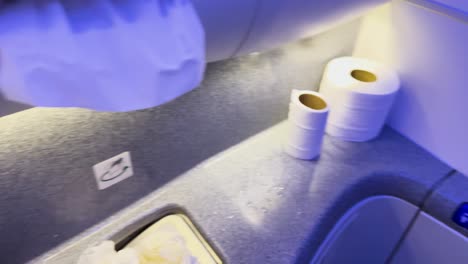 person tidying up airplane bathroom sink area