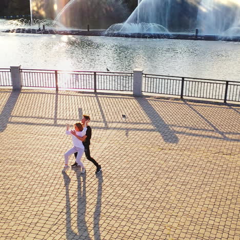 modern dancers are dancing in the street. urban lifestyle. hip-hop generation. boy's and girl's emotional moves on the video. paving stones and young dacing couple at fontain background. aerial view. young beauty dances with handsome boy.