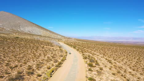 Aerial-over-an-ATV-dune-buggy-dirt-vehicle-on-a-dirt-road-through-the-desert-raises-dust-and-suggests-outdoor-advanture