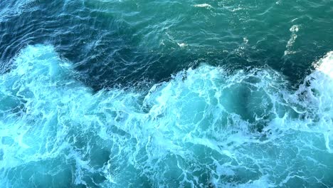 cargo ship with blue water giving rise to a white waves