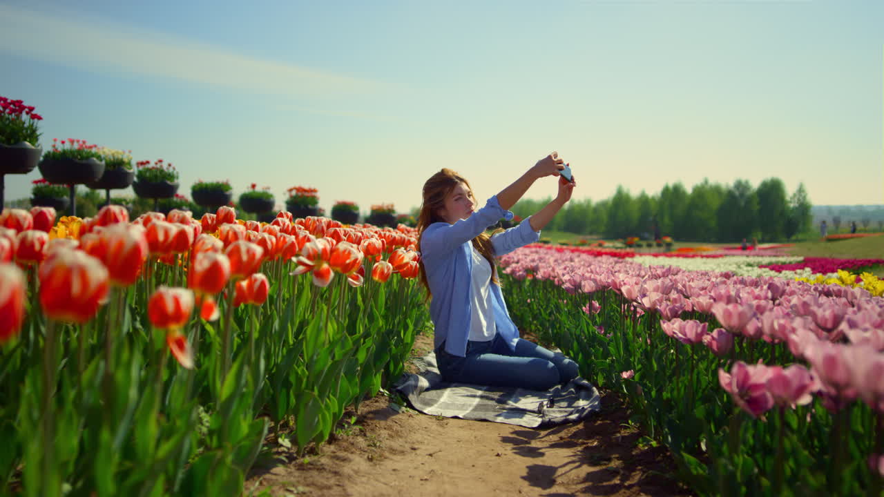 campo de tulipanes brillante y mujer joven haciendo una selfie en el fondo de la flor