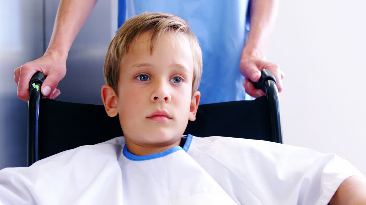 간호사 가 체어 에 앉은 소년 을 밀고 있다