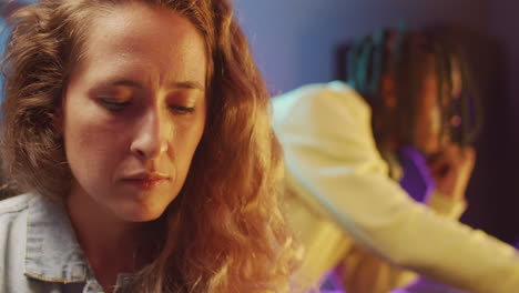 woman playing synth while working with colleague in recording studio