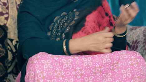 indian woman roll the black thread into a ball to prepare it for knitting