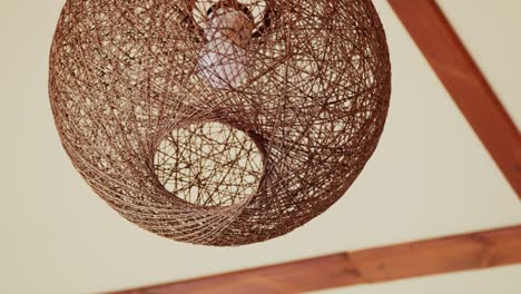 brown wicker chandelier, lampshade with bulb swinging under the ceiling