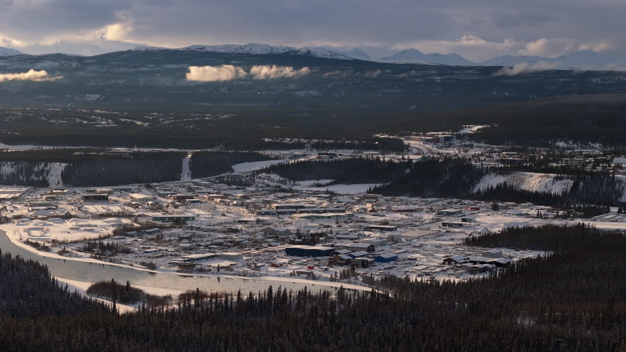 Stunning aerial view of Whitehorse, Yukon, at sunset. Snow-covered landscapes and the Yukon River glisten in golden hour light.