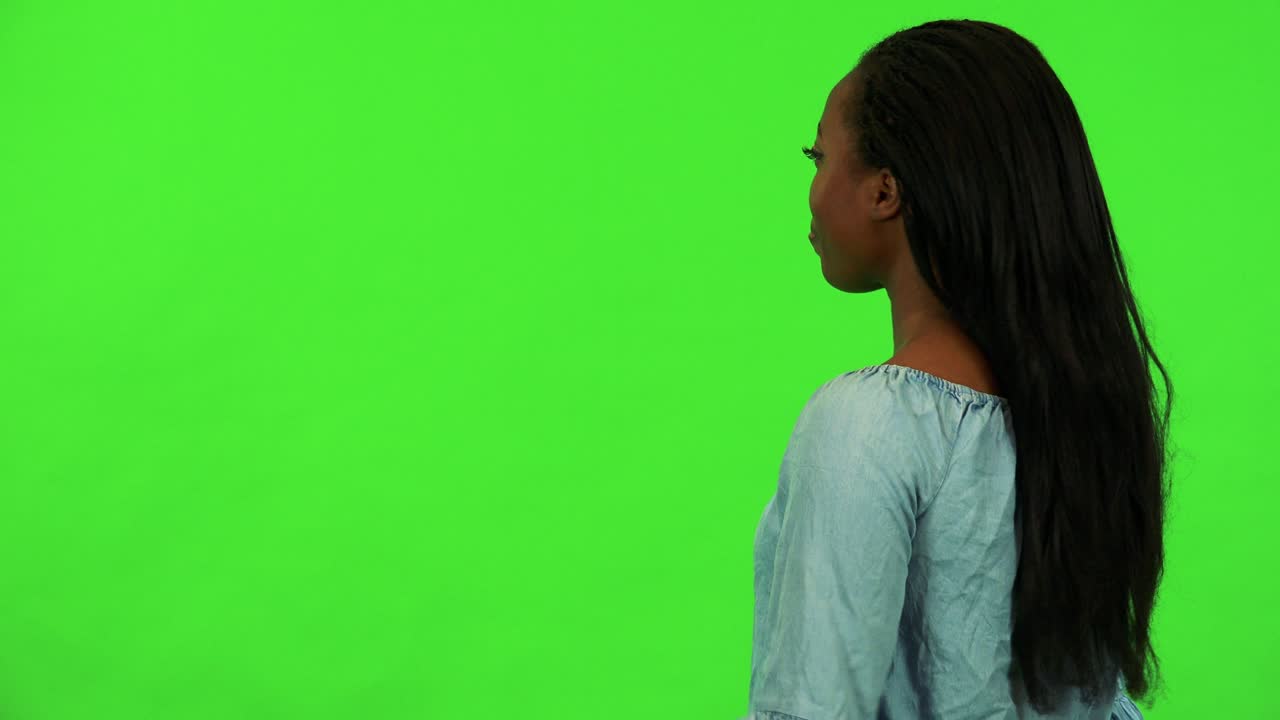 A young black woman with her back to the camera rejoices - green screen studio