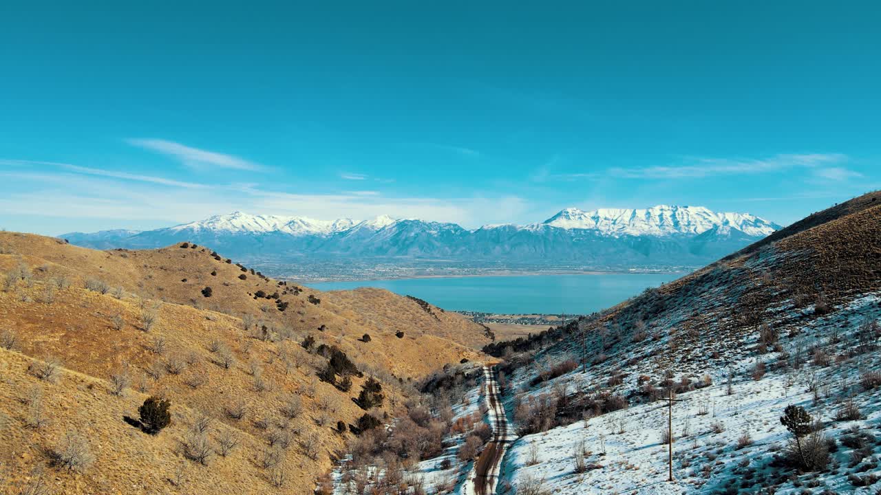 volando a través de un estrecho cañón hacia un lago en un valle con montañas cubiertas de nieve en el fondo - sobrevuelo aéreo