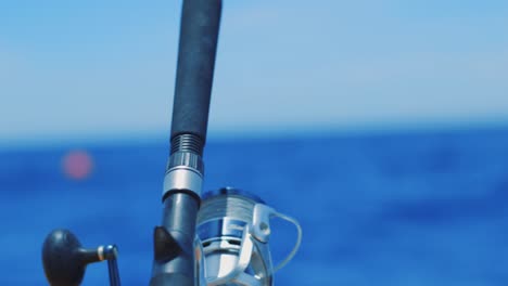 close up on fishing rod and reel with tackle swinging in soft focus background