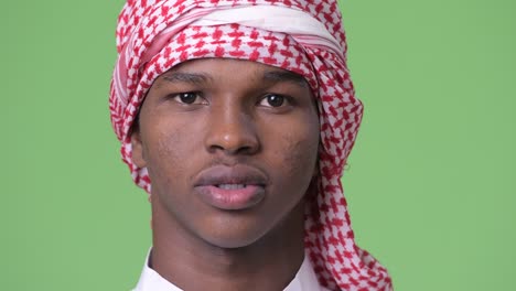joven africano con ropa tradicional musulmana contra un fondo verde