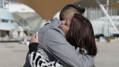 Smiling-young-couple-hugging-on-street-during-sunny-day