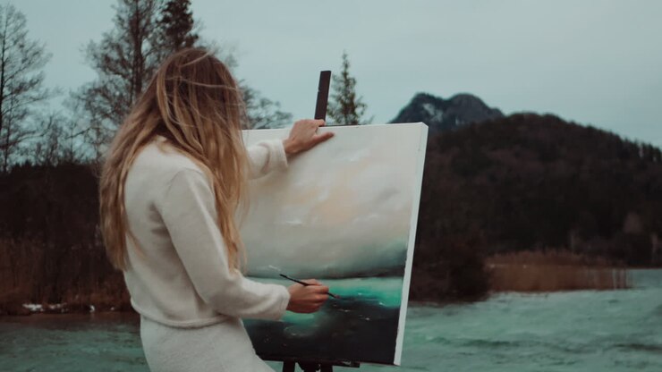 mujer pintando al aire libre junto a un lago