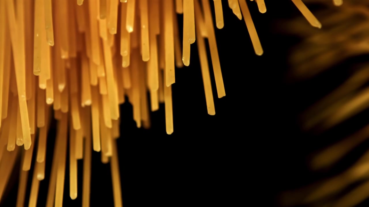 Primo piano di spaghetti secchi appesi su sfondo nero