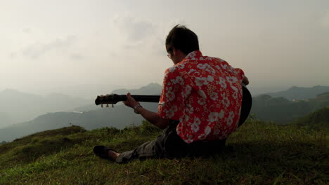 male playing guitar on hill top in beautiful nature enjoying evening breeze