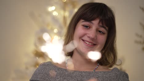 a girl smiles while holding a lit christmas sparkler